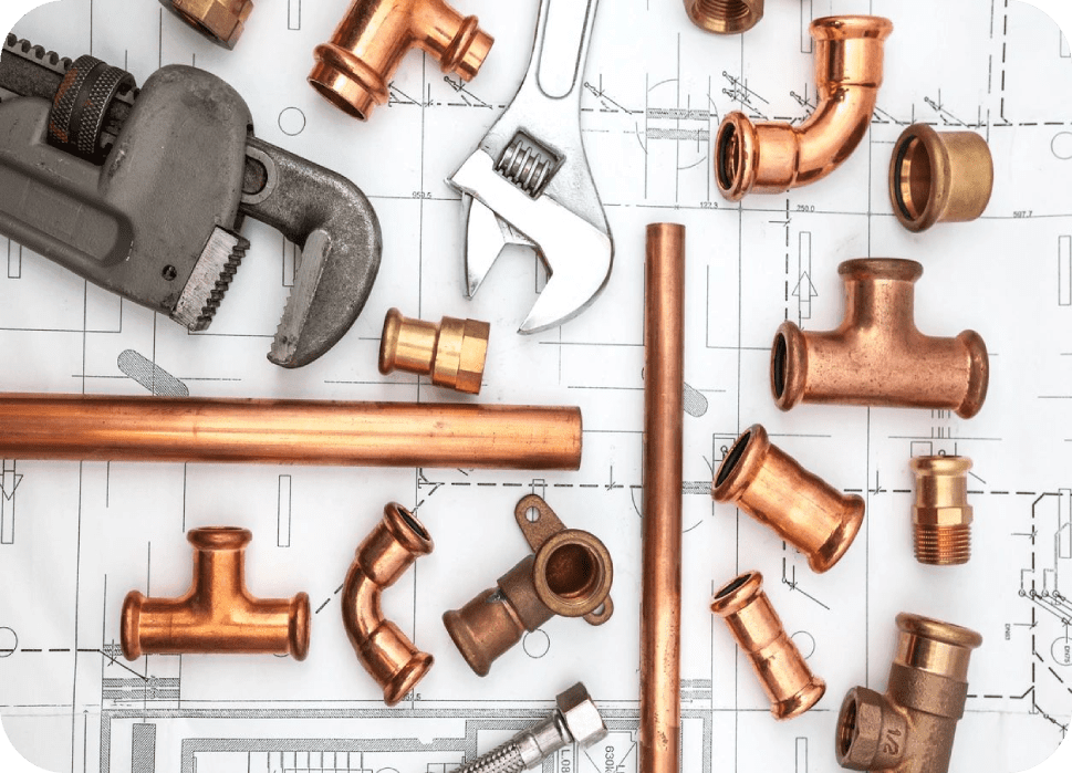 Various copper plumbing fittings and tools on a white surface.